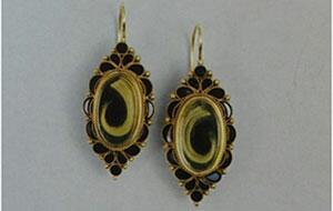 These gold mourning earrings have locks of blonde hair surrounded by tear-shaped pieces of onyx. They are from 1860-1870; a matching pin survives. 110514_History-Behind-article.jpg